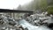 Old bridge above river. Rapids on quick mountain torrent in Alps, water is flowing over big white boulders and bubble