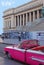 Old Bright Pink convertible classic vintage Cuban yank tank Car in front of National Capitol Building, Havana, Cuba