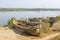 Old broken and abandoned boats on the shore against the backdrop of the river and the green forest