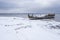 Old broken boat wreck and rocky beach in wintertime. Frozen sea, evening light and icy weather on shore like fairy tale country