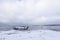 Old broken boat wreck and rocky beach in wintertime. Frozen sea, evening light and icy weather on shore like fairy tale country