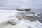 Old broken boat wreck and rocky beach in wintertime. Frozen sea, evening light and icy weather on shore like fairy tale country