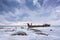 Old broken boat wreck and rocky beach in wintertime. Frozen sea, evening light and icy weather on shore like fairy tale country.