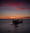 Old broken boat wreck on the shore, a frozen sea and beautiful blue sunset background.