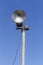 Old broken rusty street lamp against blue sky