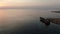 Old broken ship standing in orange sunset on Cyprus resort. Calm waters of Mediterranean Sea on sundown. Tranquility