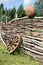 Old broken wooden carriage wheel on wattled fence