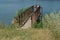 Old brown bridge with rusty iron railing over the lake water and a dam near the shore