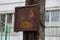 old brown electric box in rust hanging on a concrete pillar