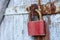 Old brown padlock on a gray door with wooden planks of cracked paint and rust. Vintage gates with metal stripes and bolts