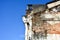 Old building cracked grungy cement brick wall on blue sky background