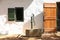 Old building with shutter window, vintage antique water pump and wooden door.