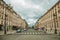 Old buildings and people in a cobblestone avenue on cloudy sky in Paris.