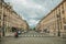 Old buildings and people in a cobblestone avenue on cloudy sky in Paris.