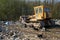 The old bulldozer moving garbage in a landfill