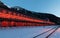 Old Canfranc train station with the facade illuminated in reddish tones on a winter night with snow on the tracks, Huesca, Spain