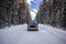 Old car standing in the middle of empty road going through big forest coverd with white snow, Banff national park Canada