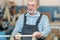 An old carpenter with a mustache and glasses is concentrating on his work.