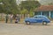 Old cars and three people in Cuban village in rural central Cuba