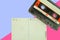Old cassette tape audio with paper to write song name and text on pink background.