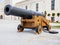 An old cast iron artillery gun on wooden wheels stands