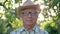 Old Caucasian Man With Glasses And Hat Portrait Against The Sunset In The Garden