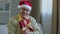 Old Caucasian senior mature 60s man in eyeglasses male wearing Christmas Santa red hat grandfather grandpa at home couch