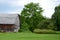 Old cedar sided country barn with red wheel carriage in front of
