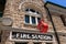 Old central fire station. Red round signal at the facade of the building. Heritage building built with stone and bricks, it opened