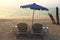 Old and cheap plastic sunbeds and umbrella on the beach