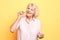 Old cheerful happy woman touching her face skin with sponge,