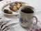 Old chipped cup with black coffee on rustic tablecloth with plat