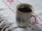 Old chipped cup with painted forget-me-not with black coffee on