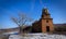 An old church, a tree and a road nearby, clear blue sky, sunny day