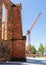 Old church walls and construction crane. Construction next to the church. City infrastructure. Under the blue sky.