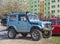 Old classic veteran tired blue 4wd car Suzuki Jimny with long exhaustion pipe parked