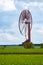 An old, closed wind farm standing alone in a field. Object against the sky with tiny clouds.