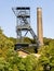 Old coal mine tower and industrial chimney in green environment