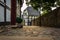 Old cobblestone alley, half-timbered houses on the left and a stone wall right on the edge of the picture, Hattingen