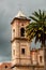 Old colonial stone church tower with palm tree