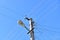 Old concrete electric pole for transmission of wired electricity with lamp post on a background of a cloudy blue sky. Obsolete me