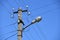 Old concrete electric pole for transmission of wired electricity with lamp post on a background of a cloudy blue sky. Obsolete me