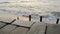 Old concrete embankment with wooden posts against the backdrop of sea waves with a sunny path in the evening