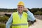 Old construction worker in work attire smiling call gesture