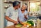 Old couple in kitchen, wine and happiness, cooking healthy food together in home with vegetables. Drink, smile and