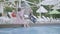 Old couple lying on sunbeds near the pool on the background. Little funny girl with pigtails sitting on the edge of the