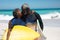 Old couple with surfboard at the beach