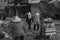 Old couple in traditional clothes are walking down a street and a female seller is managing her stall in a street of Ho Chi Minh C