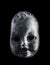 Old cracked creepy doll head isolated on black