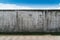 Old cracked gray cement or concrete wall with blue sky as background. Grunge plastered stucco  textured background